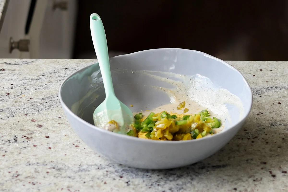 adding jalapeños and seasoning to the bowl