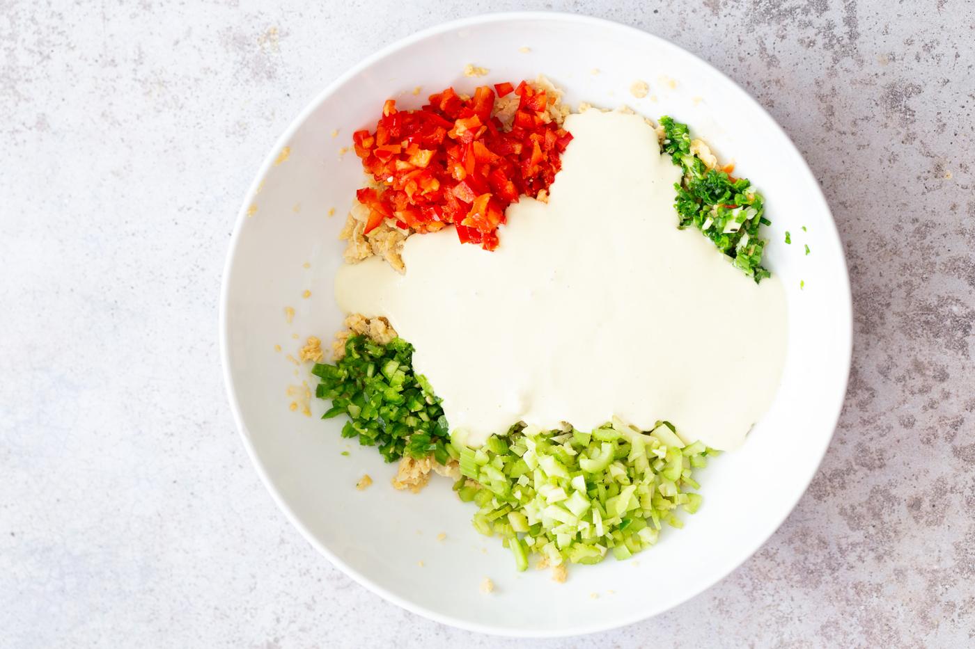 creamy dairy-free tofu dip being added to chickpea salad ingredients