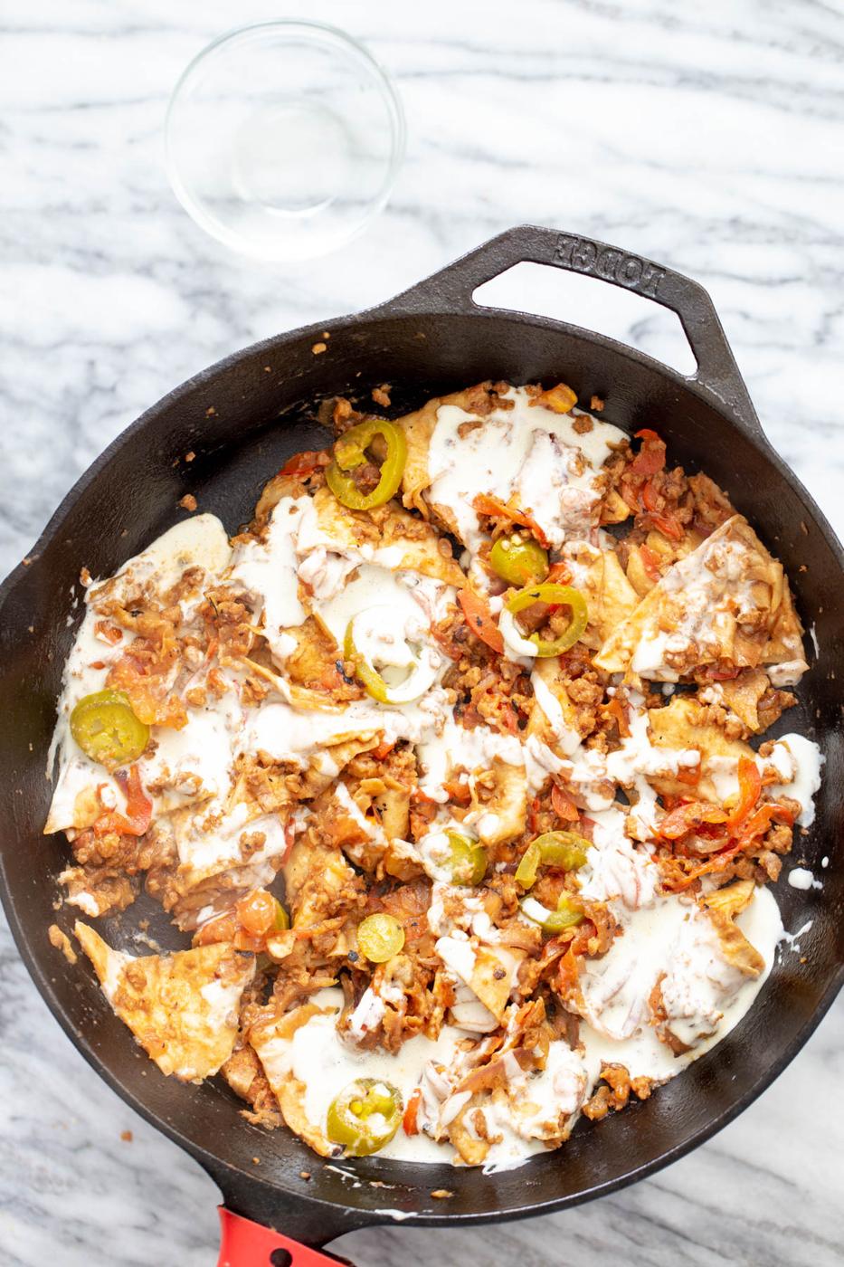 jalapeno popper cream being poured over veggies and veggie crumbles to make jalapeno popper skillet