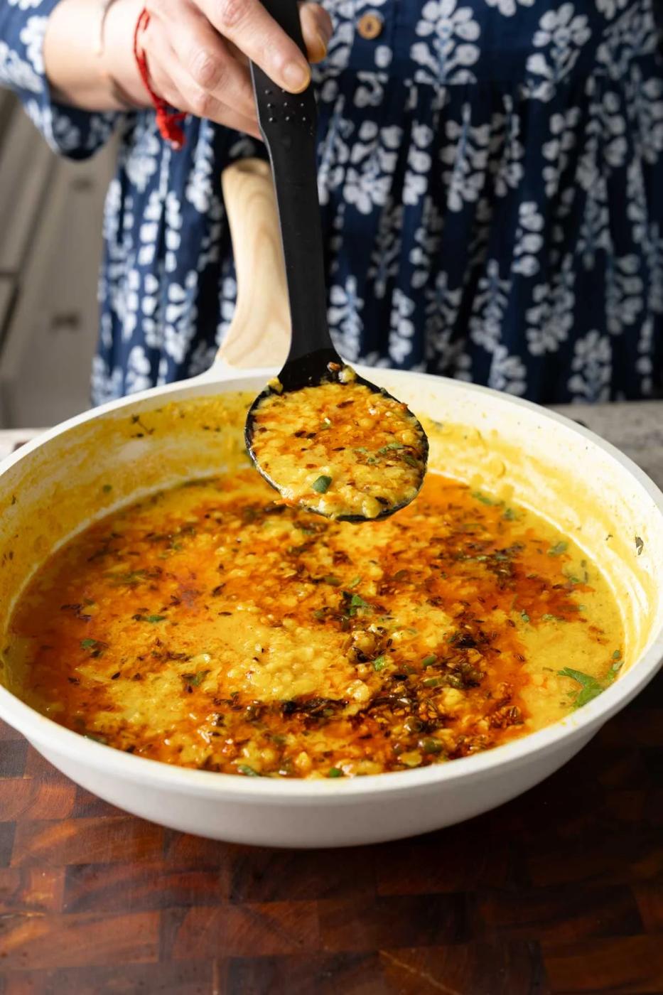 spoon serving jeera dal from the pan