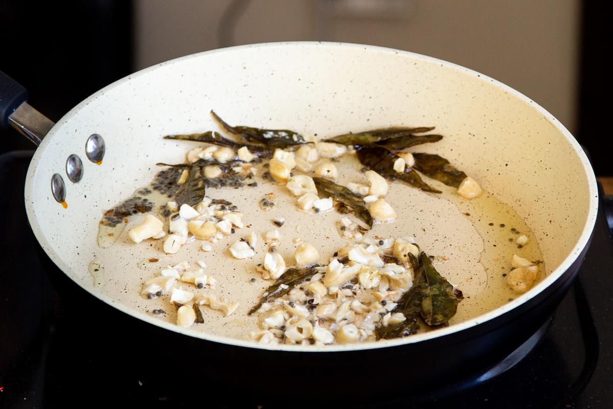 nuts being added to tempered spices in a pan