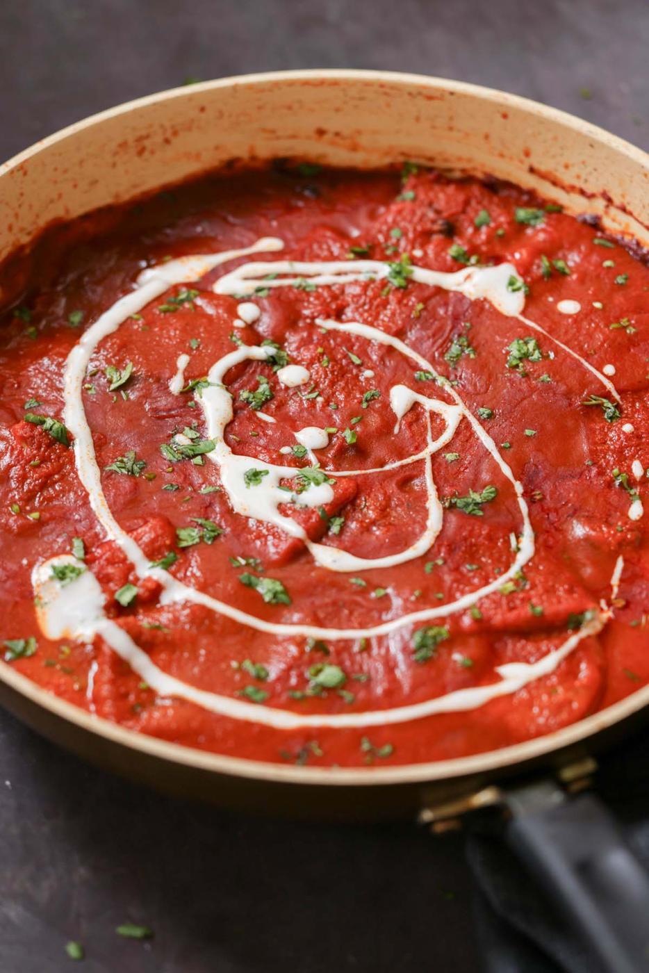 pan of vegan Kashmiri lal paneer topped with non-dairy yogurt
