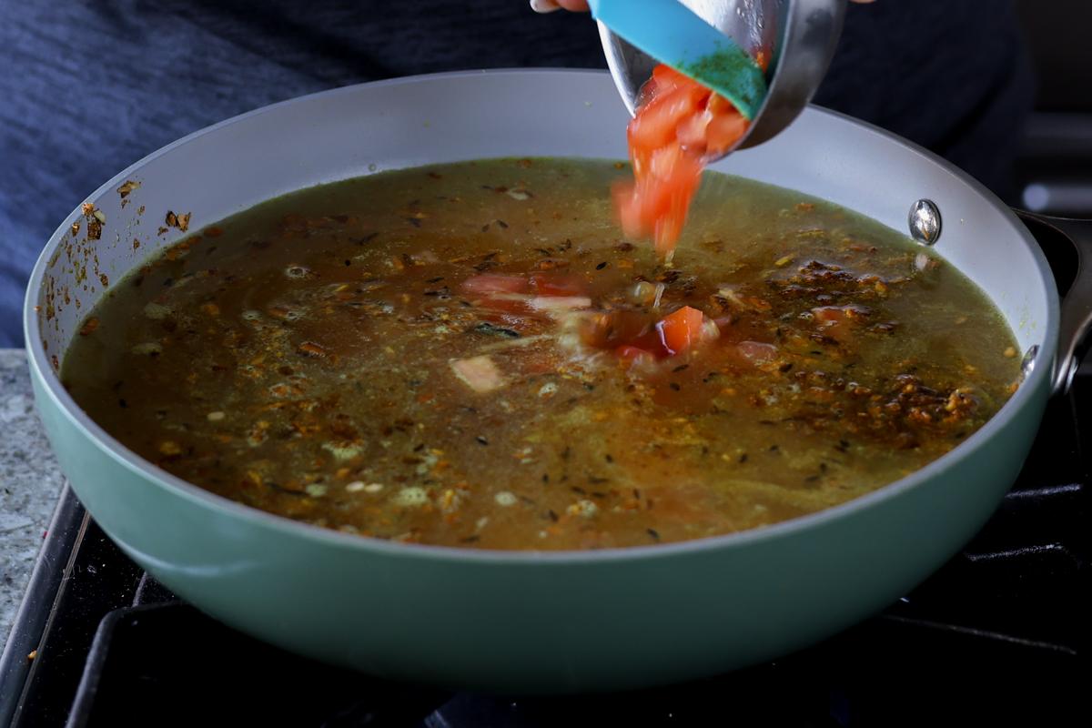 adding tomato to the pan