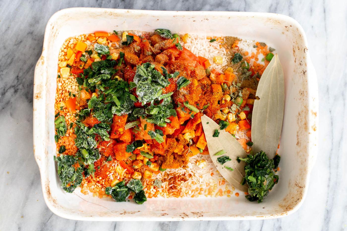veggies being added to rice and lentils in a casserole dish