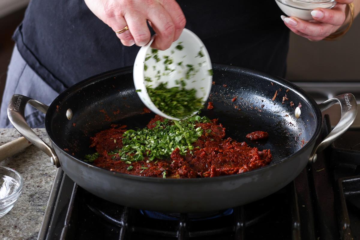 adding chopped greens to the pan