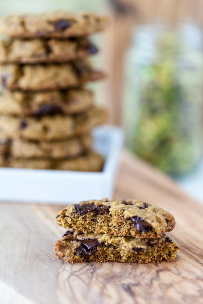 broken vegan pistachio cookies with chocolate with stack of cookies in background