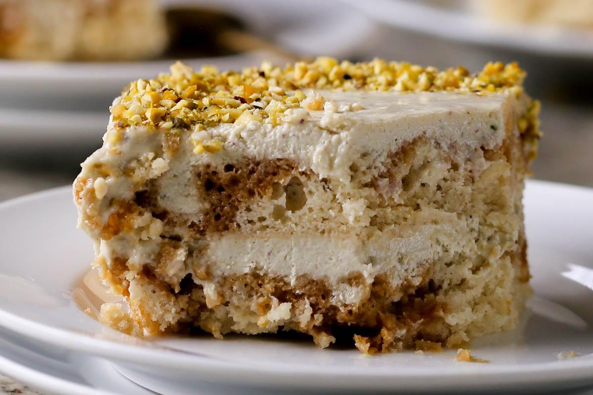close-up of a slice of Indian tiramisu on a white plate with a bite taken out