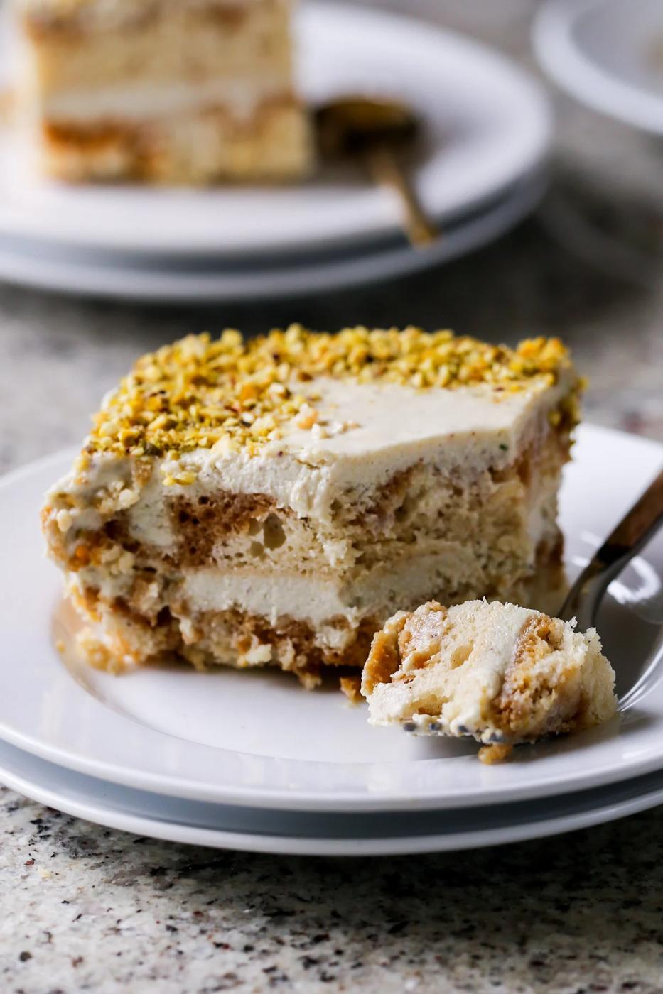 slice of Indian tiramisu on a white plate with a bite taken out