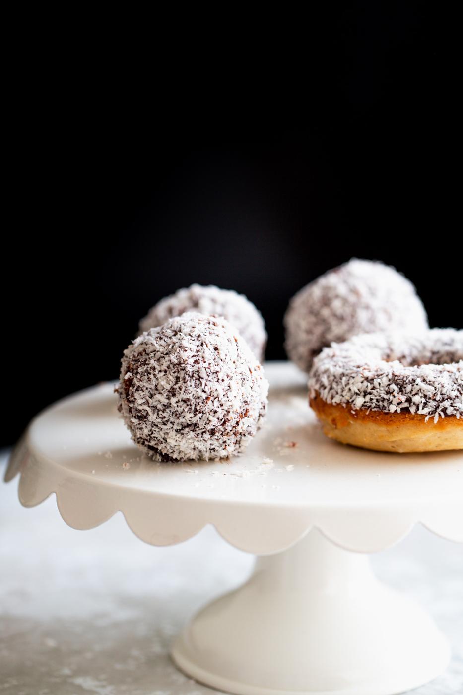 vegan lamington donut holes and baked donuts on a white cake stand