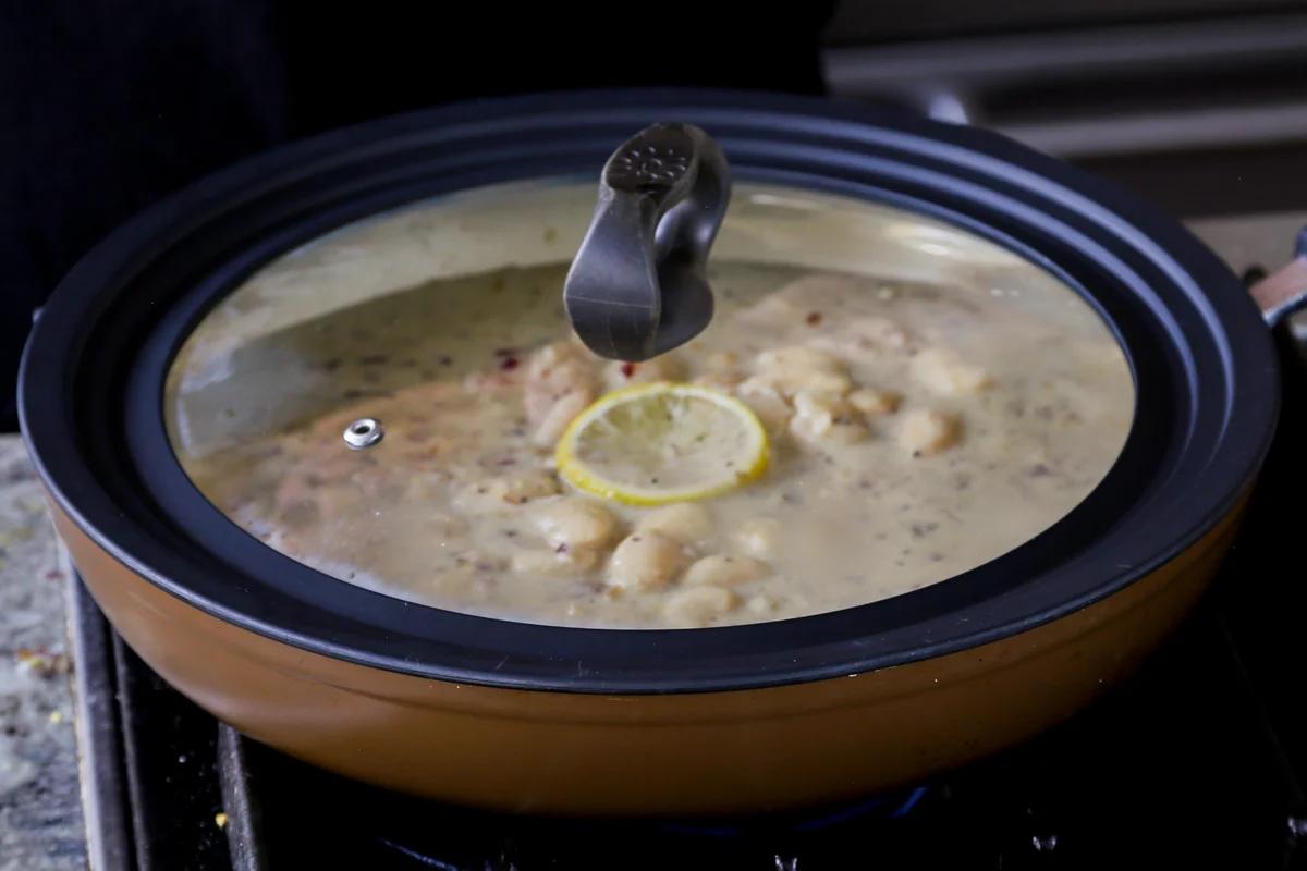 simmering the beans in the garlic sauce with the lid on