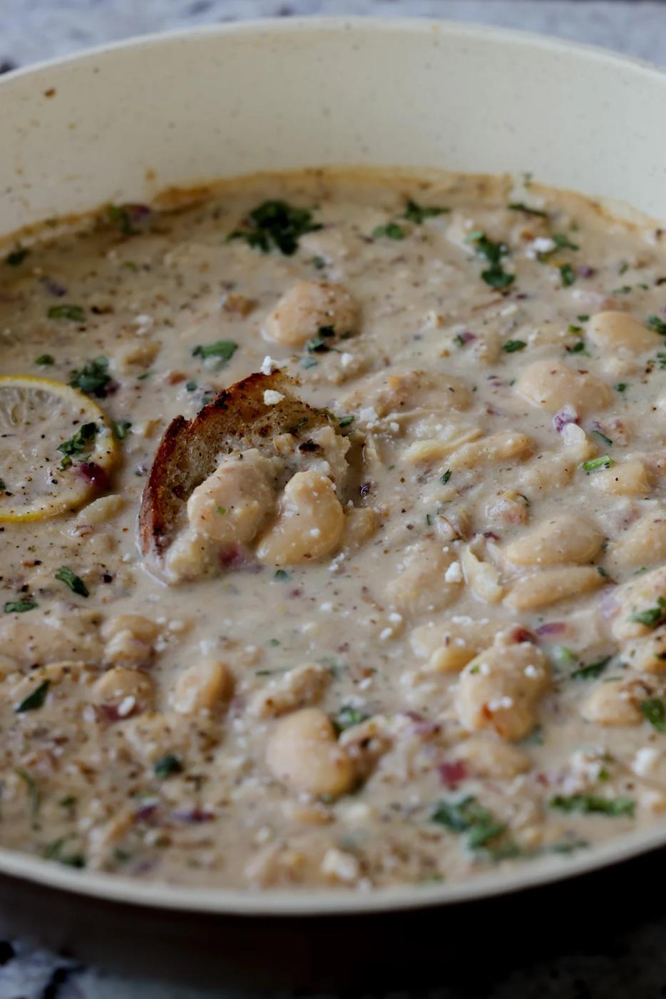 lemon garlic butter beans in a pan with a piece of bread