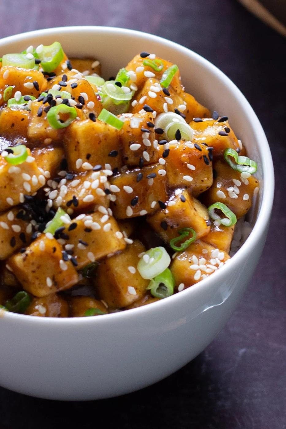 close-up of a bowl of lemon pepper tofu topped with sesame seeds and green onions