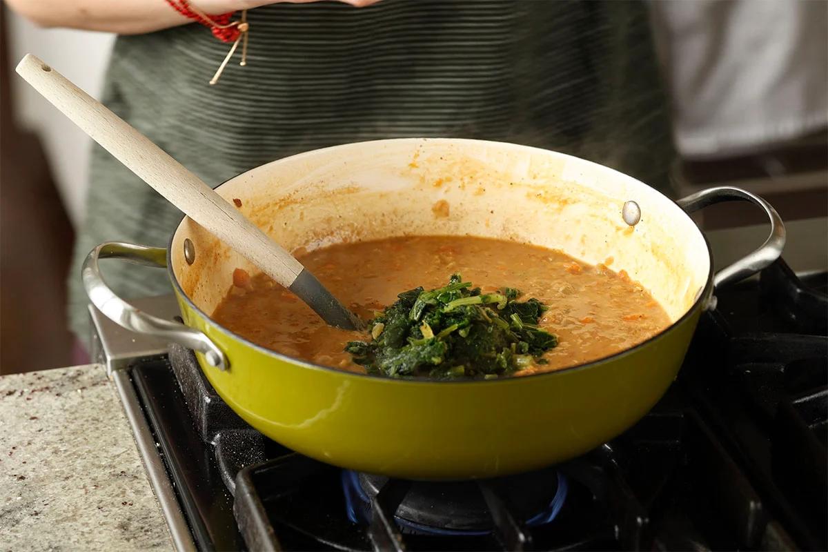 adding spinach to the lentil soup