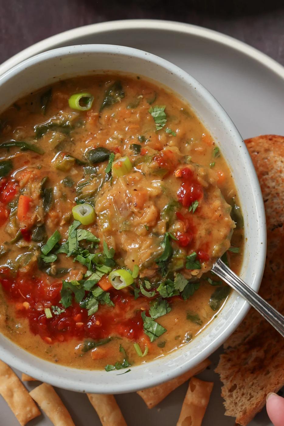 close-up of a spoon scooping a bite of lentil and spinach soup