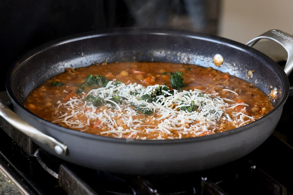 adding spinach and vegan parmesan to the pan