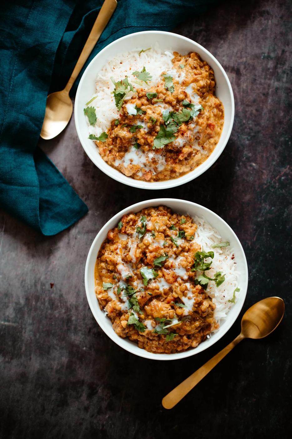 two bowls with rice topped with creamy coconut curry lentil casserole