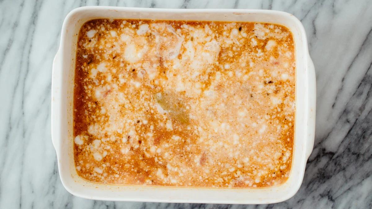 broth and coconut milk being added to spices and onion garlic mix in casserole dish