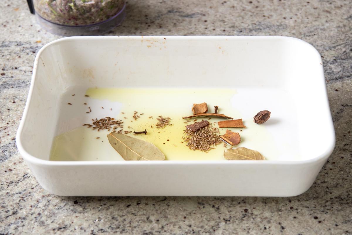 oil and whole spices in the baking pan