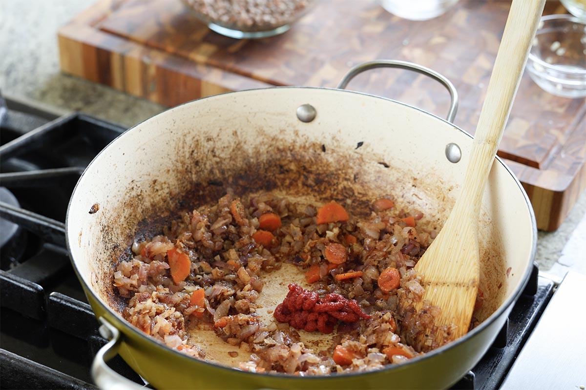 adding tomato paste to the pan