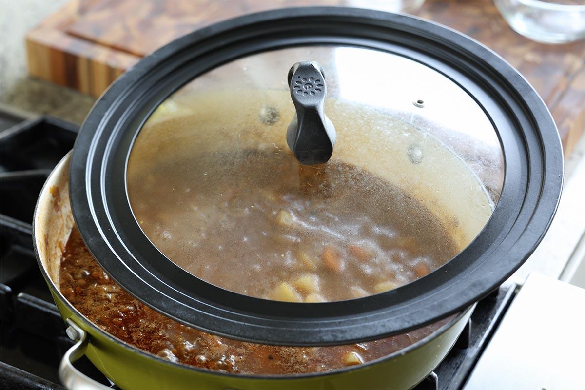 covering the pan with the lid to cook the potatoes