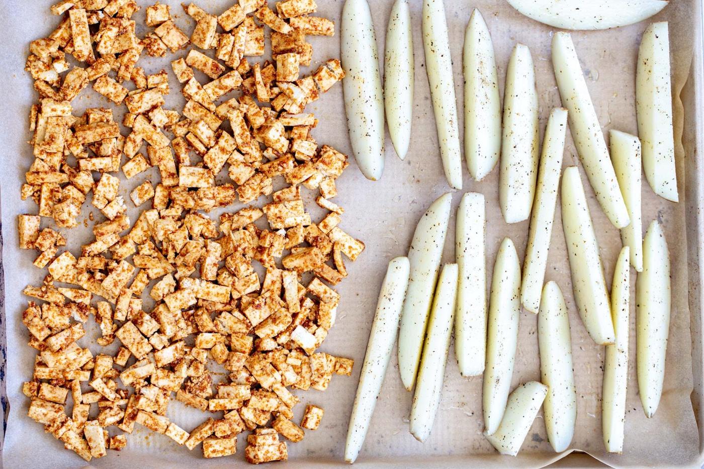 baking sheet with marinated tofu cubes and seasoned potato wedges