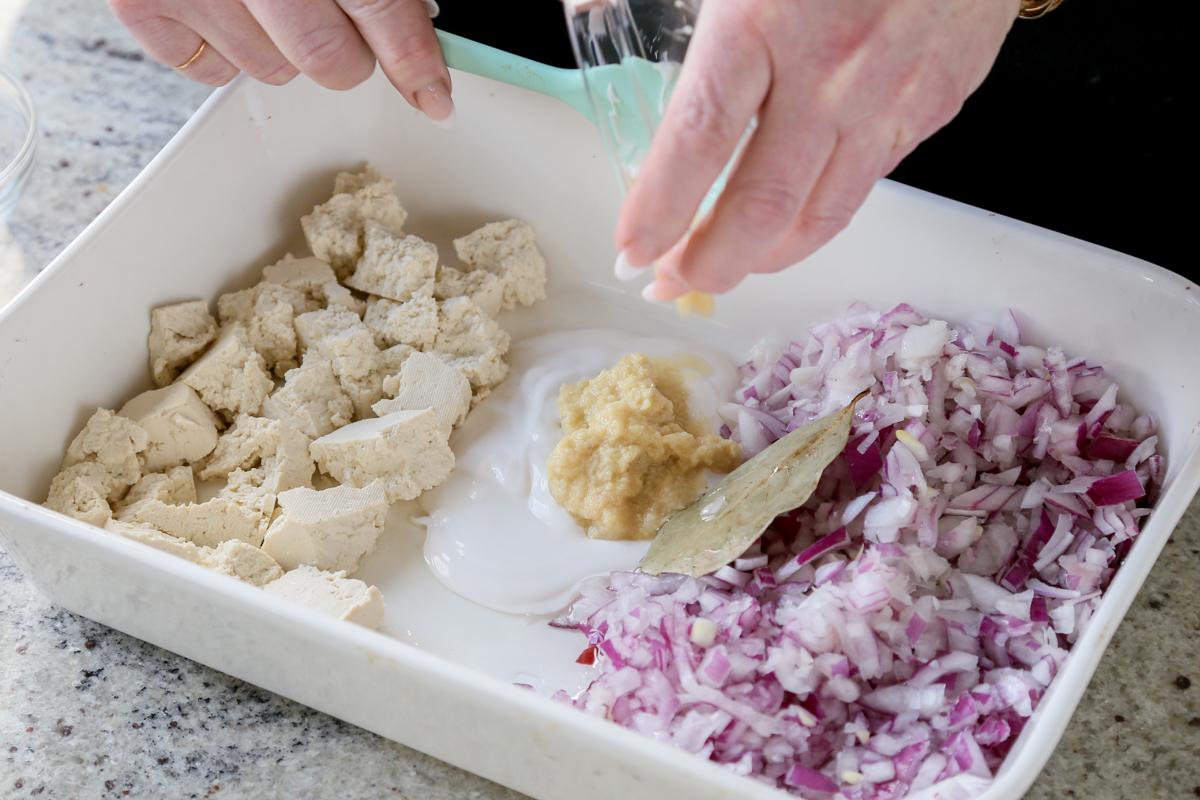 adding the ginger garlic paste and non-dairy yogurt to the center of the pan