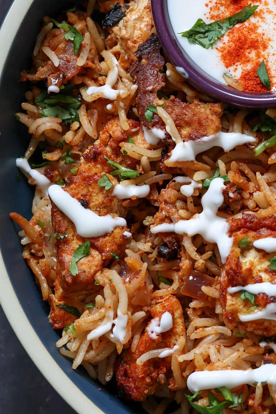 close-up of Lucknowi biryani in a bowl topped with raita