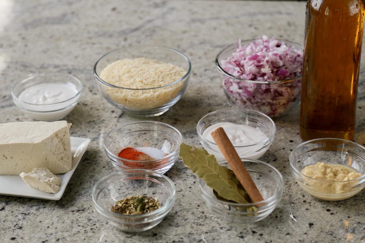 rice, spices, and other biryani ingredients in bowls on the kitchen counter
