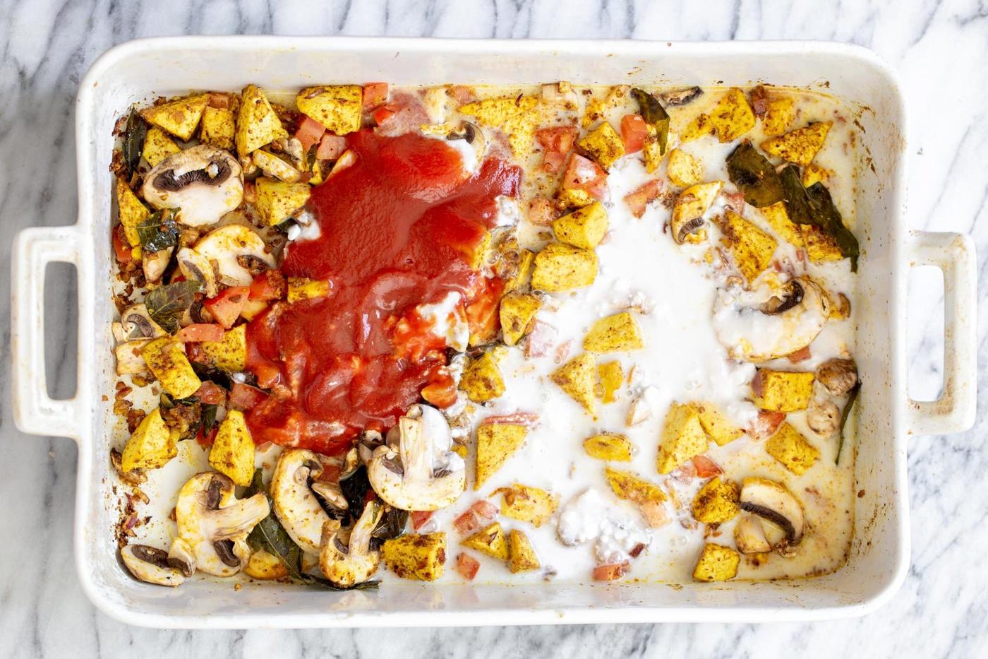 tomato puree and coconut milk being added to baked tofu