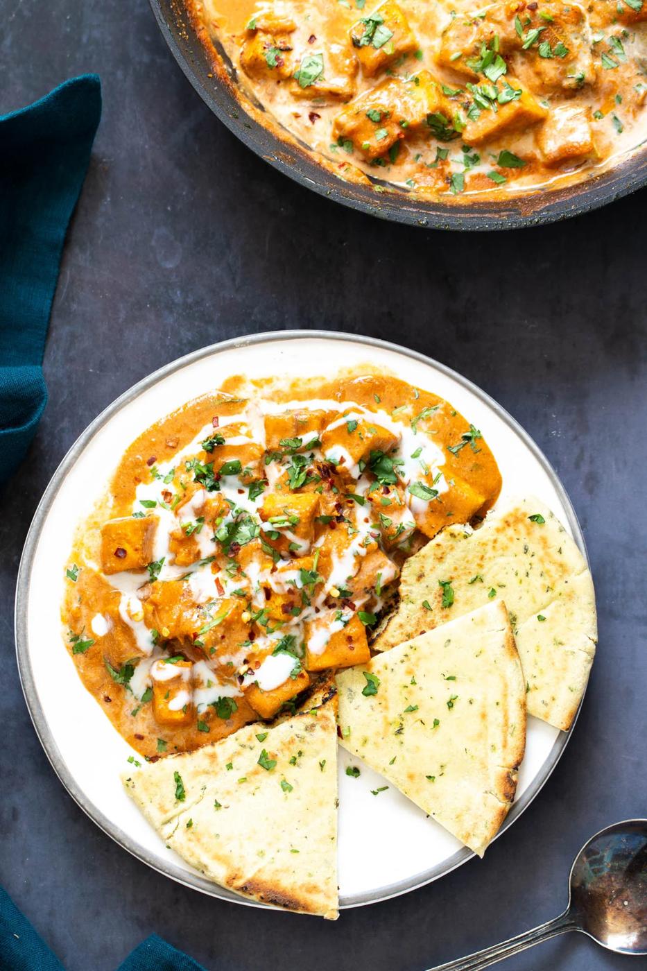 overhead shot of a serving of malai tofu curry served with a side of quartered naan