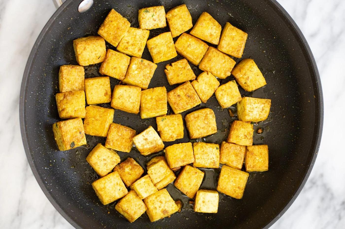 tofu cubes being sauteed in a s frying pan