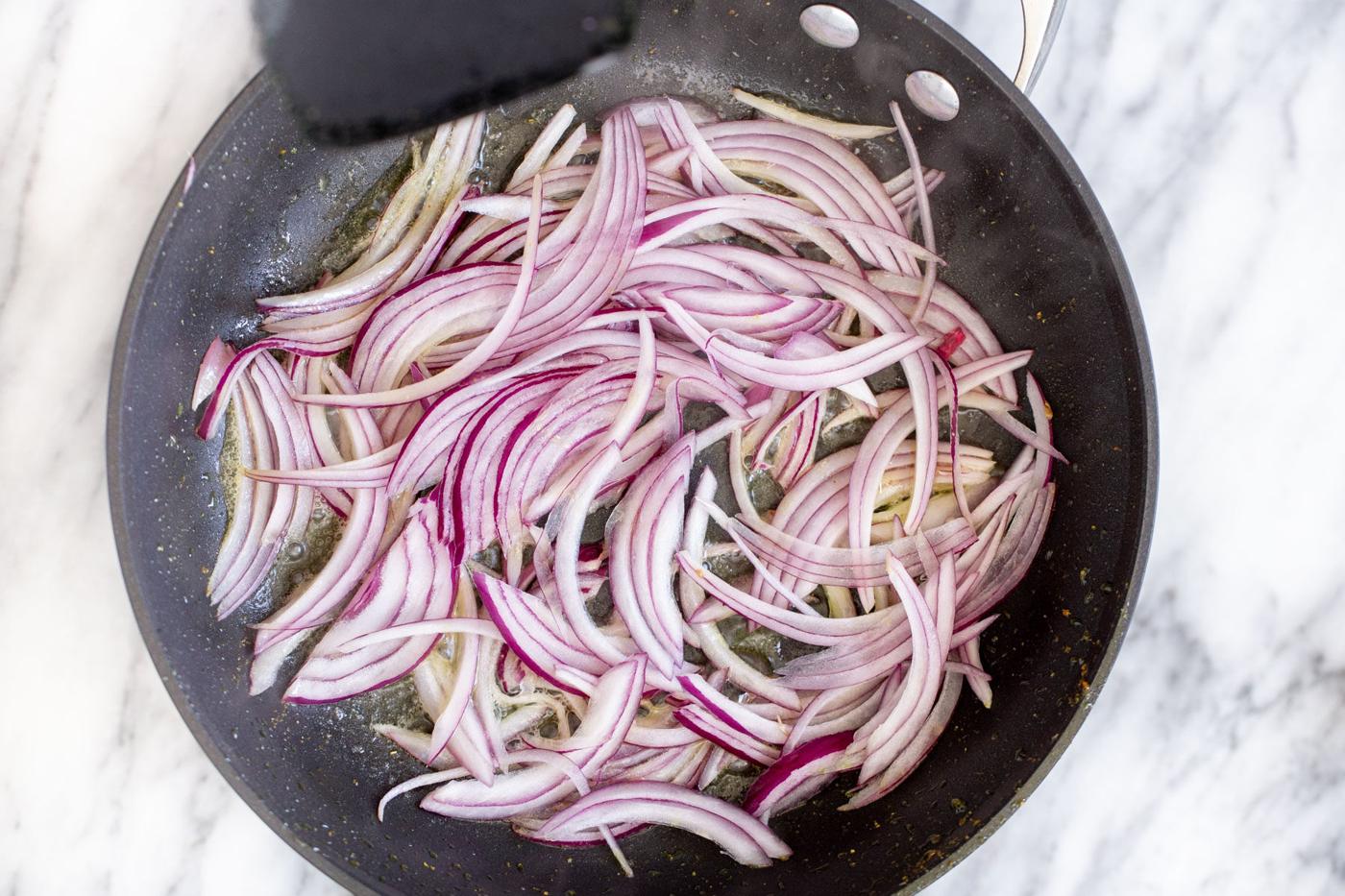 onion sliced in a black sauteeing pan