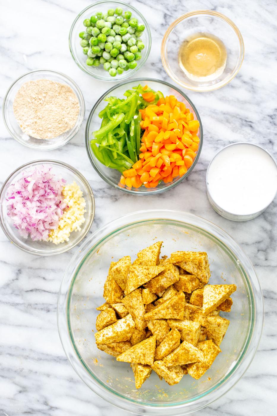 marinated tofu and several sides of veggies on a marble countertop