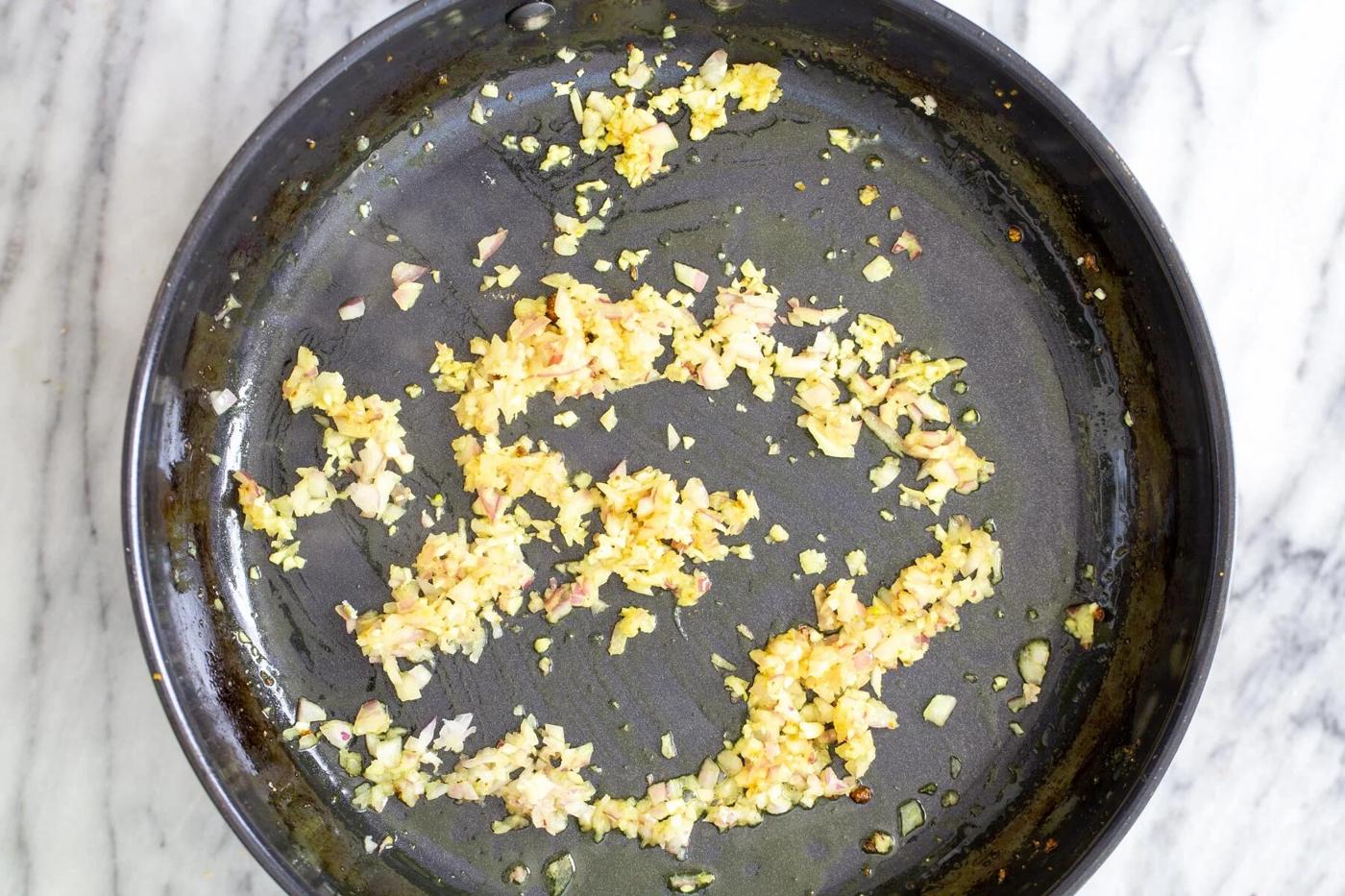 ginger and onion sauteeing in a black skillet