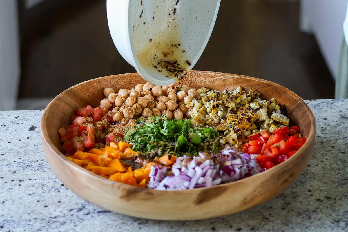adding spiced oil to the mango chickpea salad