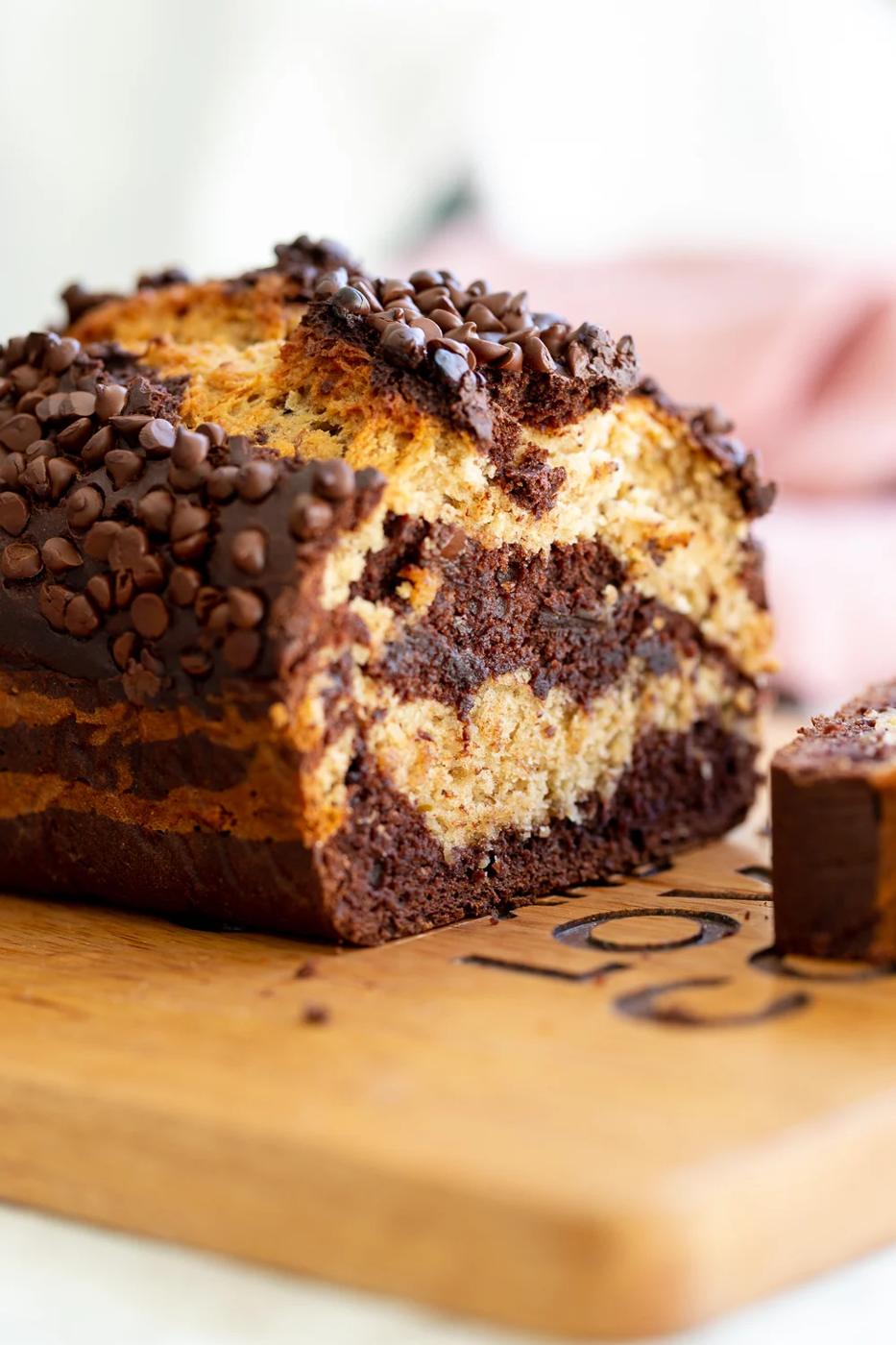 a sliced loaf of marbled vegan chocolate banana bread topped with chocolate chips on a cutting board