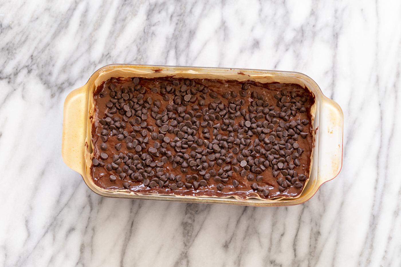 chocolate banana bread batter being topped with vegan chocolate chips for making banana bread