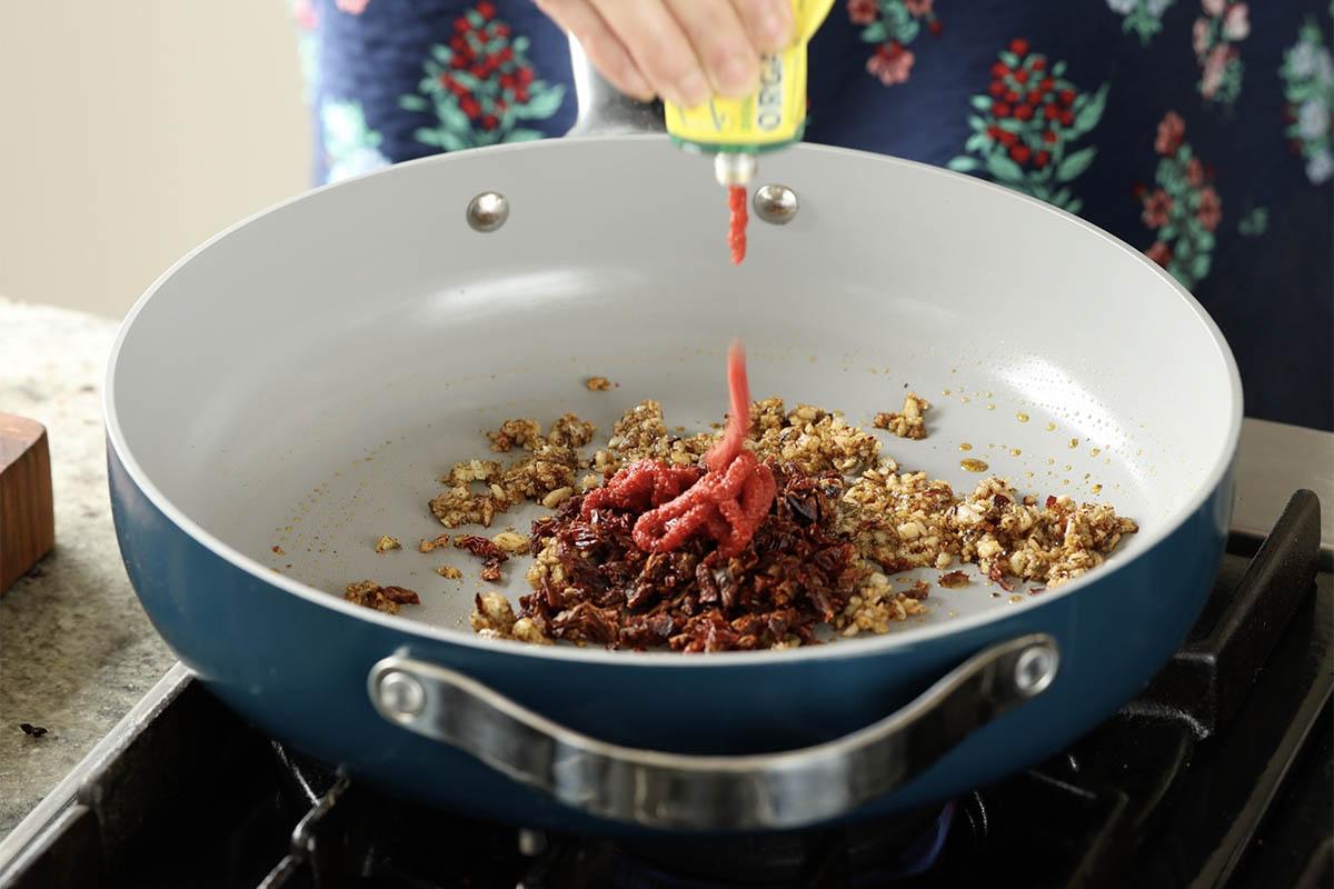 adding sun dried tomato and tomato paste to the pan