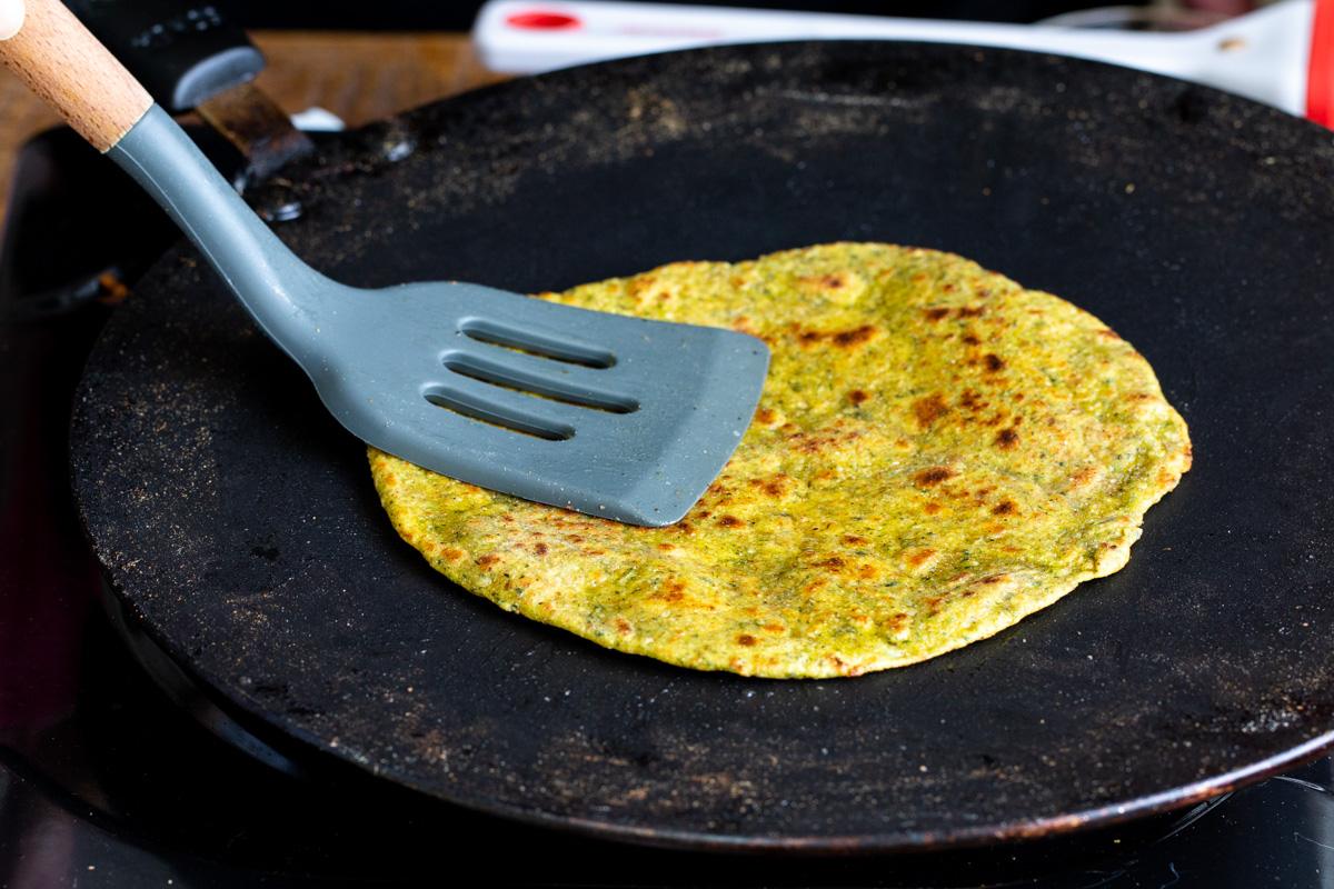an Indian flatbread being prepared in a black skillet
