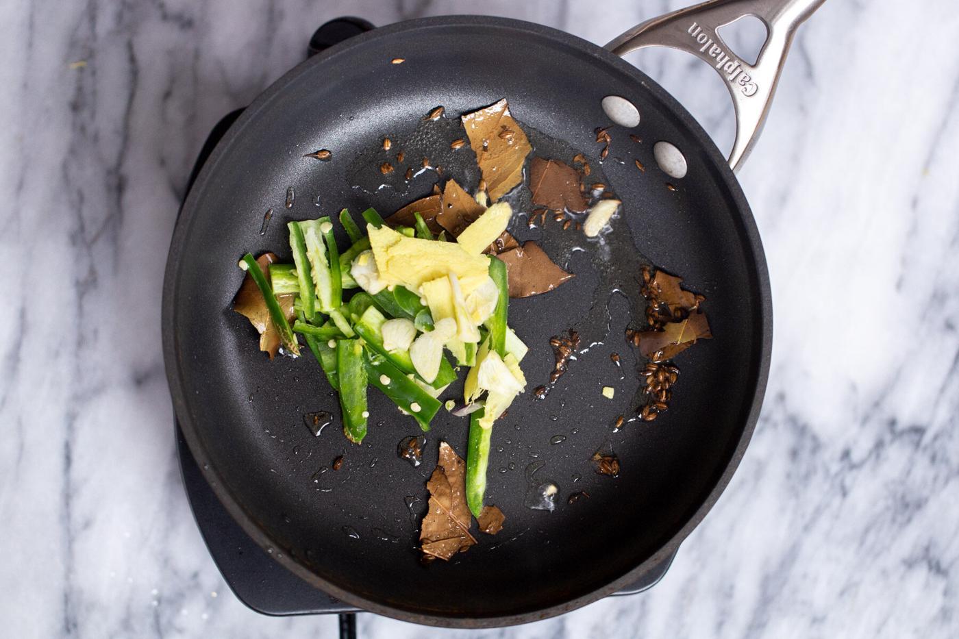 ginger and green chile being added to sauteeing pan with hot oil