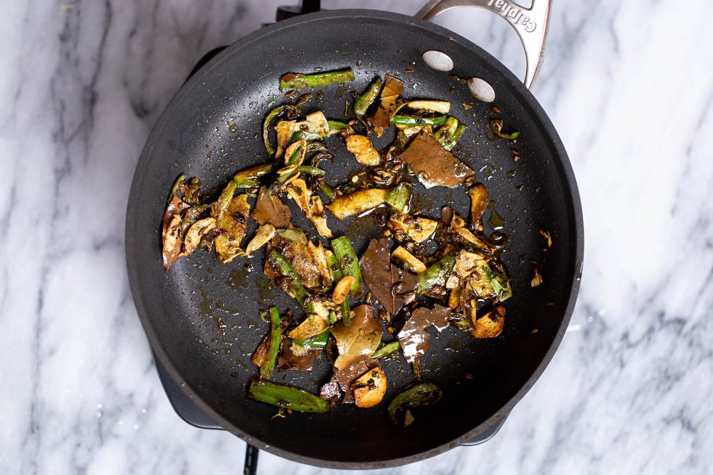 tempered green chile and ginger in a black sauteeing pan