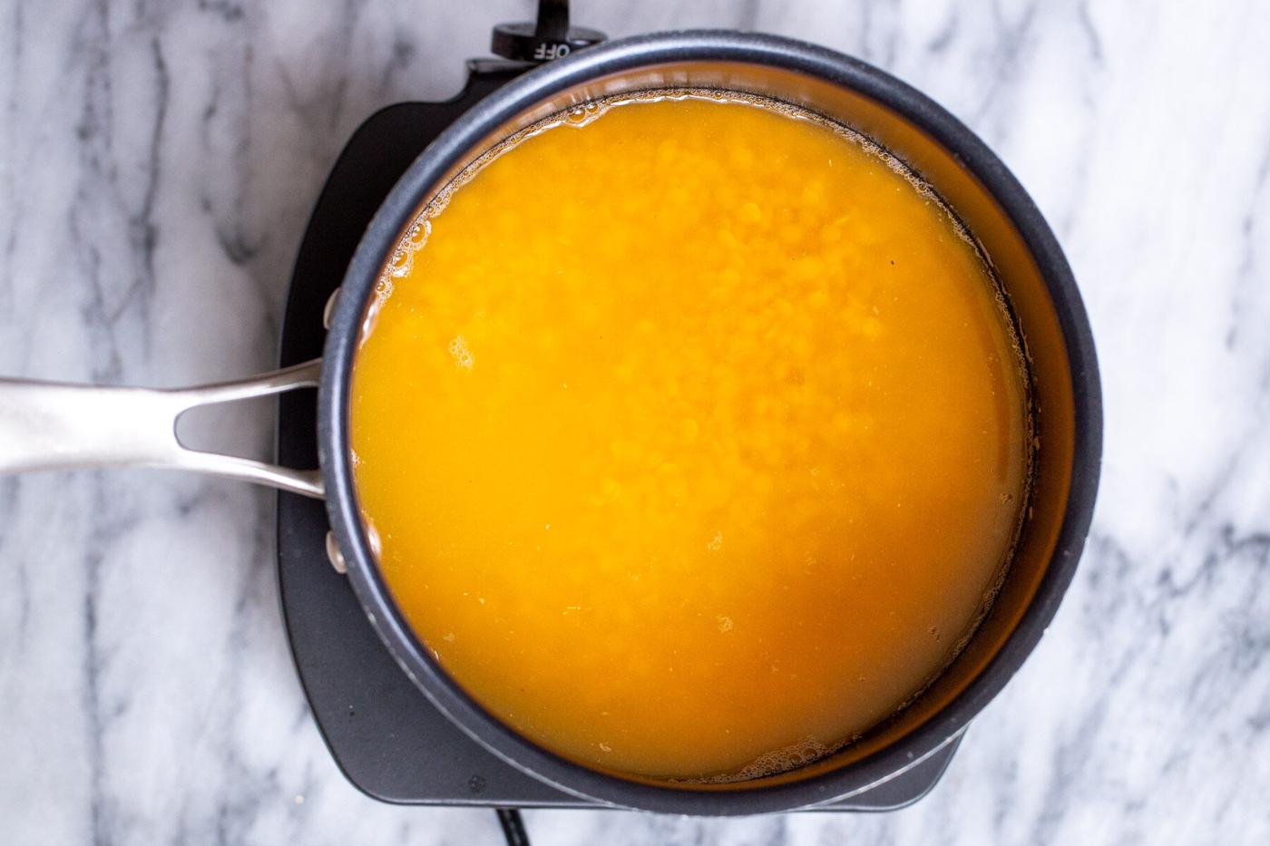 red lentils being cooked in a pot for making masoor dal tadka