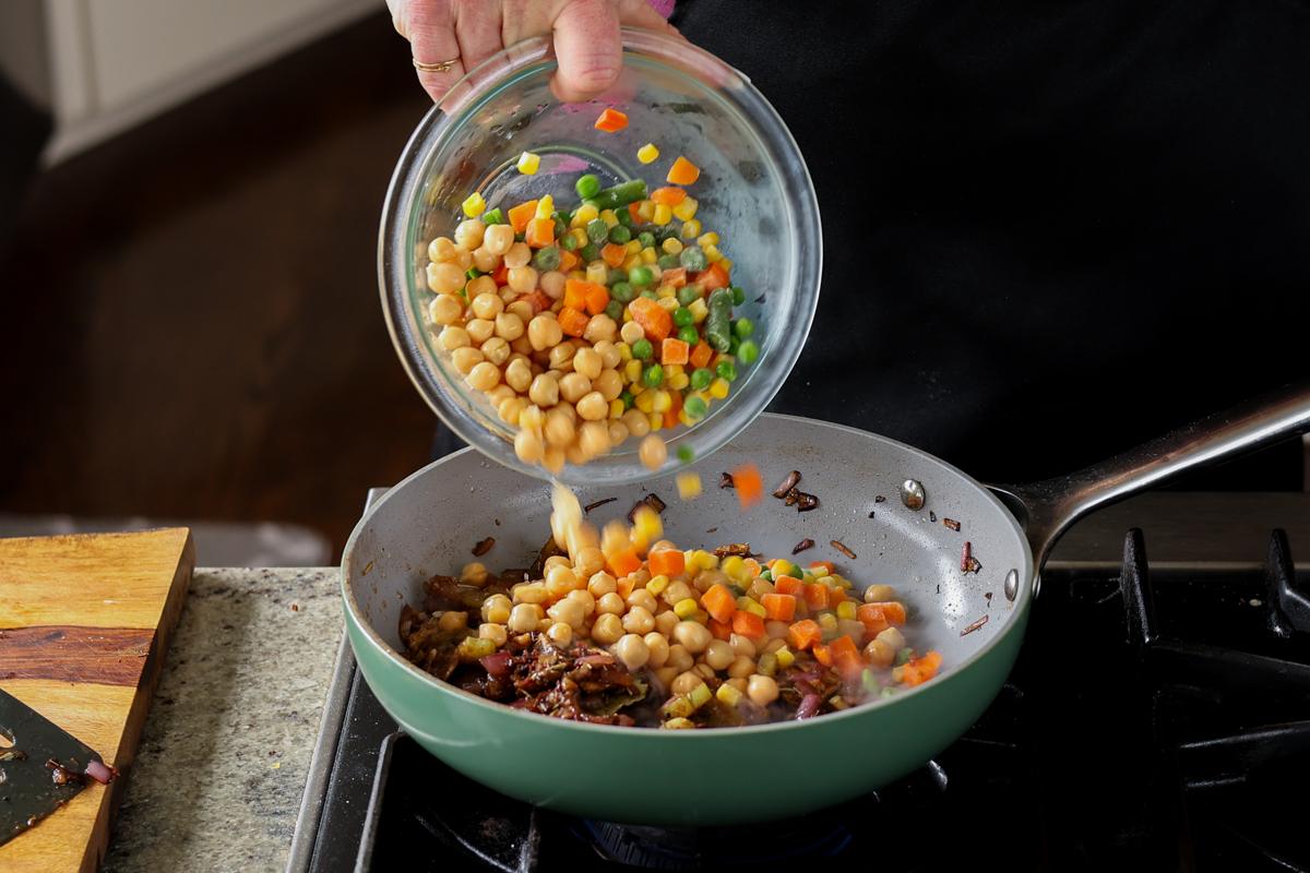 adding chickpeas and veggies to the pan