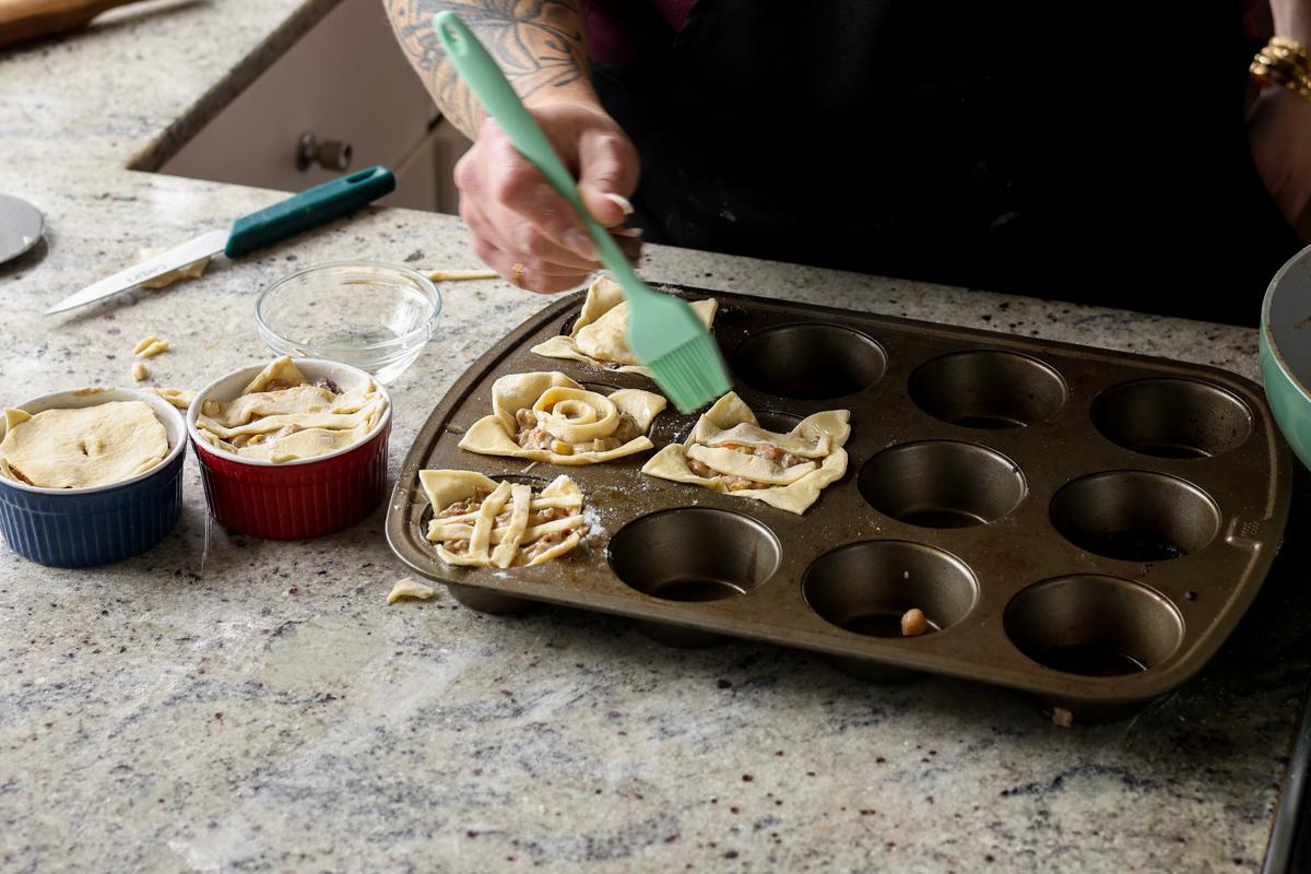 adding crust to the tops of the mini pot pies and brushing on oil before baking