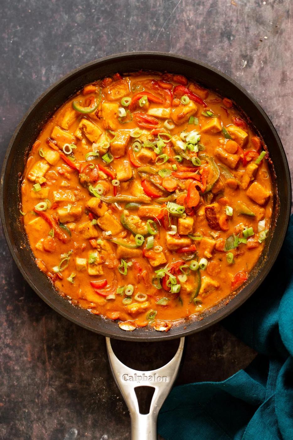 tofu and veggies in a skillet in creamy peanut butter sauce
