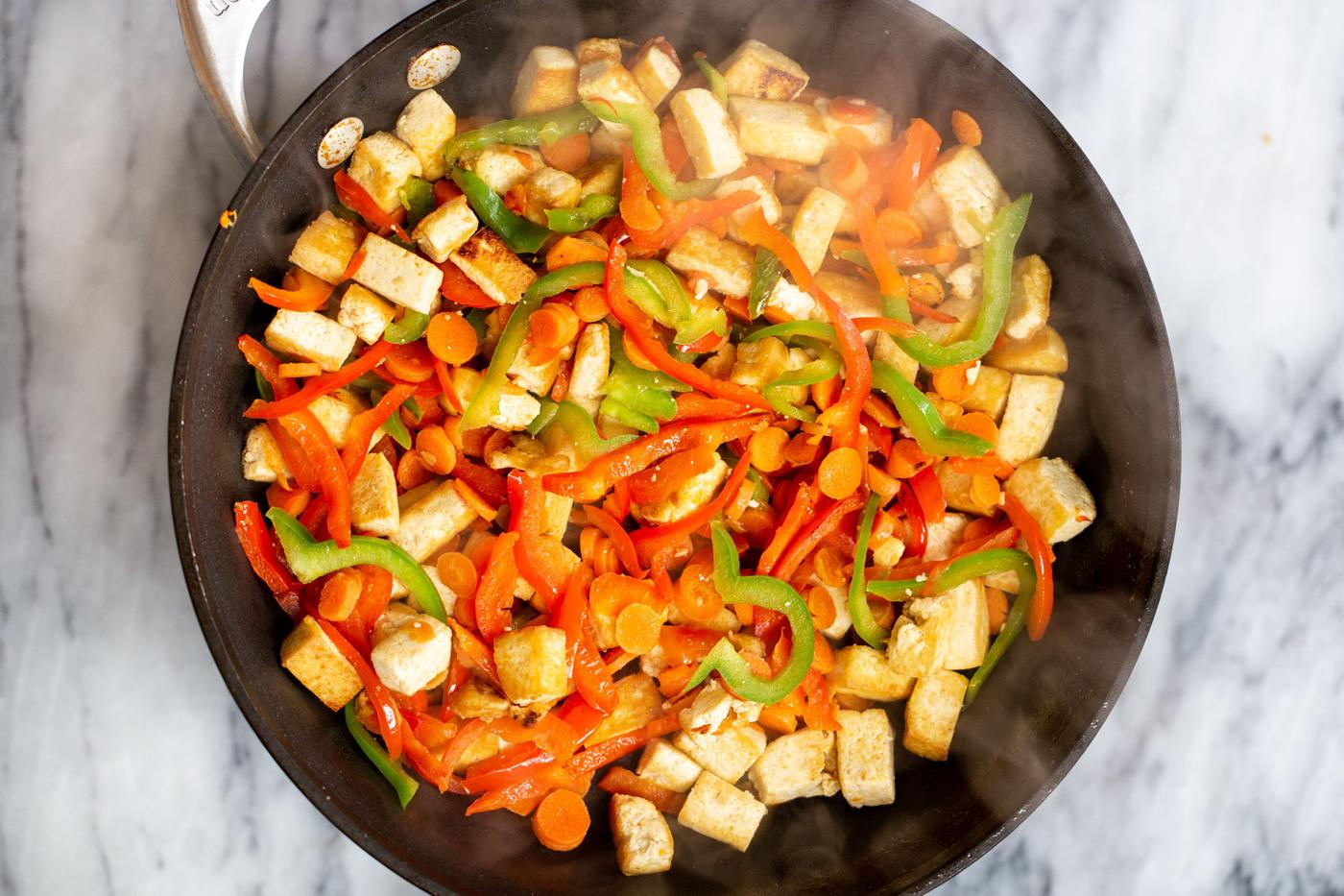 tofu cubes and bell peppers in a black skillet
