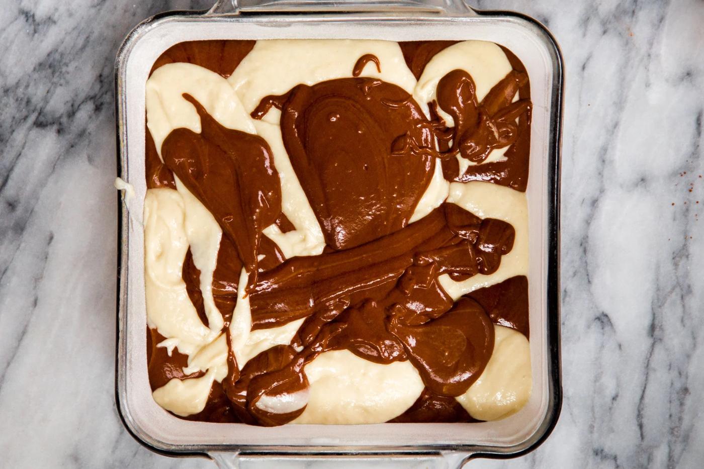 vanilla and mocha cake batters being swirled in a pan to make marble cake