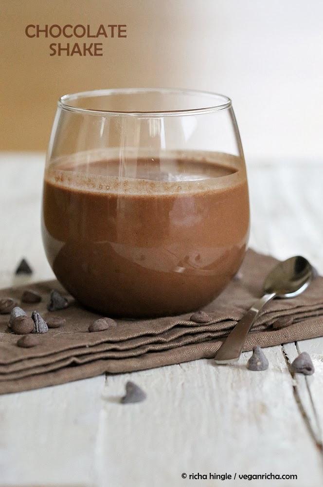 side view of a glass of vegan chocolate milkshake with chocolate chips on the side