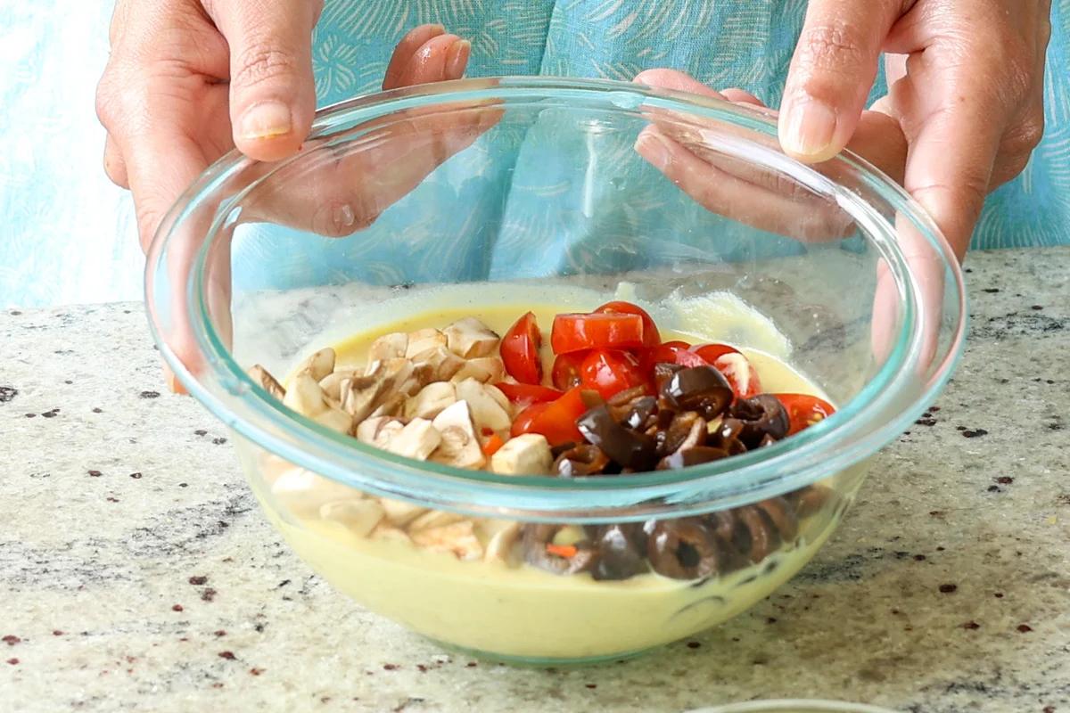 adding pizza ingredients to the batter