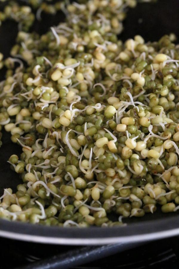 sprouted mung beans being sauteed in a pan